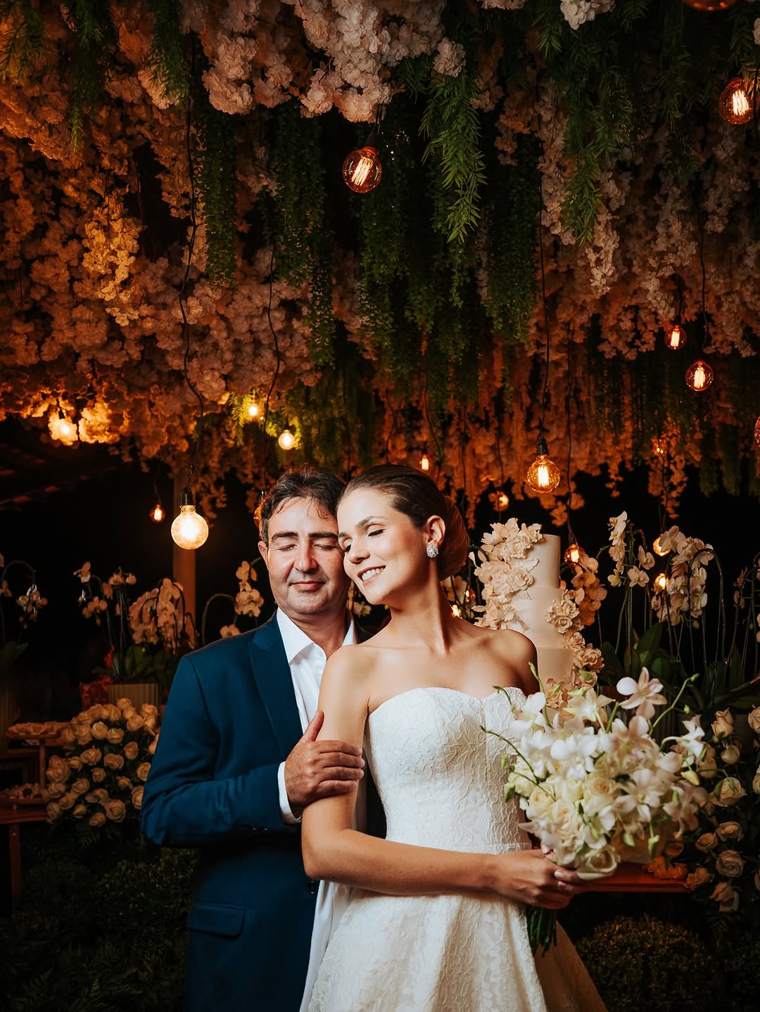 Casal de noivos sob decoração floral e luzes